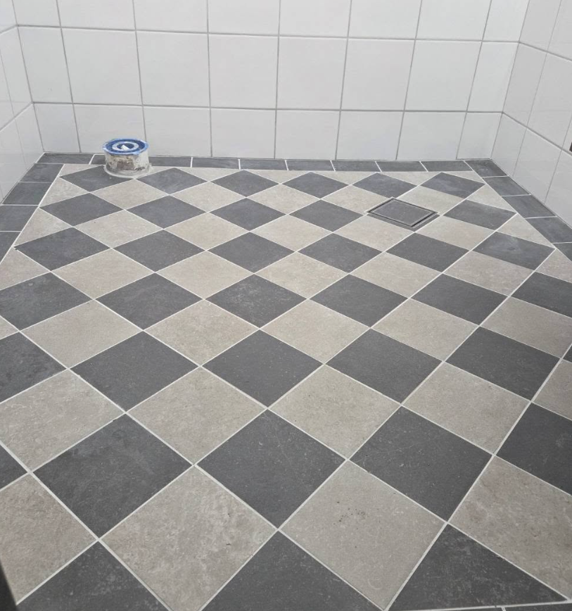 Nyrenoverat badrum med schackrutigt klinkergolv och vita kakelväggar.